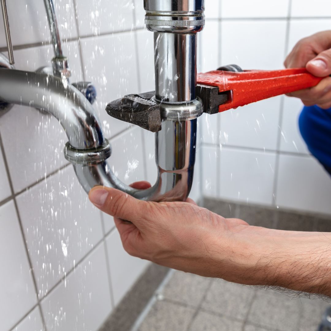Plumber repairing a leaking pipe fitting